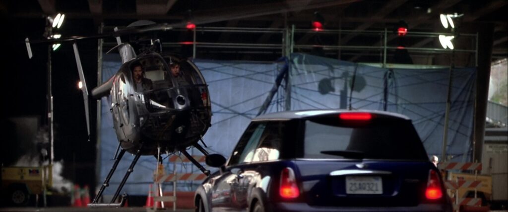 A high-speed Mini Cooper chase unfolds as the heist team is pursued by a helicopter in The Italian Job (2003). In this thrilling sequence, Charlie Croker and his crew use the Mini Coopers to navigate through Los Angeles while executing their daring gold heist revenge plan.