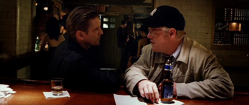 Barry Pepper and Philip Seymour Hoffman in a dimly lit New York bar, discussing the fate of their friend Monty Brogan before his prison sentence.