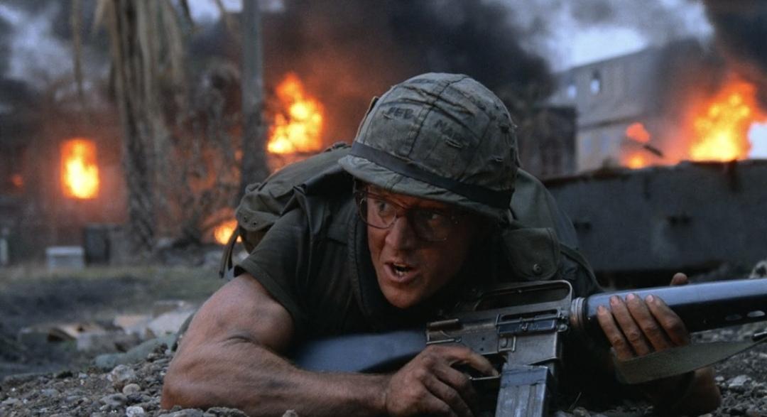 Sergeant "Cowboy" (Arliss Howard) crawls through the battlefield amidst flames and destruction during the Battle of Huế